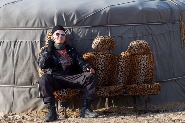 White sunglasses on leopard-print van seats outside a gray felt yurt