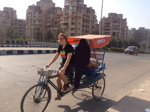 Pedaling a cycle rickshaw while its driver, printed as a silhouette, rides as the passenger