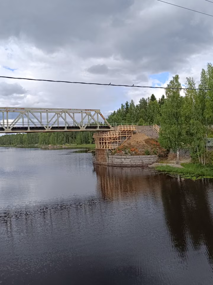 A steel truss bridge across a dark river, scaffolding at one end