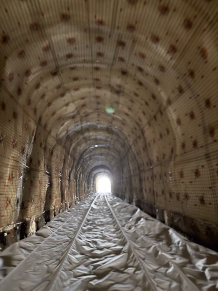 A railway tunnel lined with panels, daylight at the far end